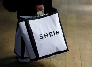 Consumidor segura sacolas de compras com logotipo da Shein em Paris, França